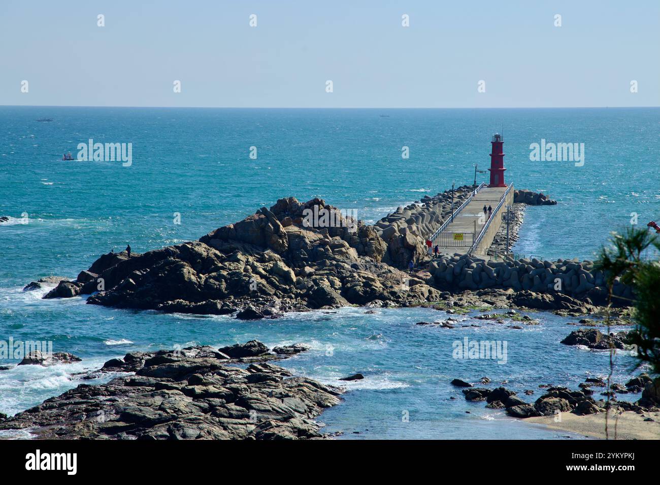 Yangyang County, Südkorea - 3. November 2024: Ein roter Leuchtturm steht am Rande einer felsigen Mole im Hafen von Naksansa und bietet einen beeindruckenden Auftritt Stockfoto