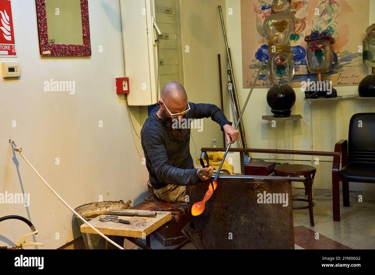 Venedig, Italien; 17. Oktober 2024: Ein schwieriger Prozess der Herstellung einer Murano-Glasfigur in einer historischen venezianischen Werkstatt. Der geschickte Handwerker formt sorgfältig Stockfoto