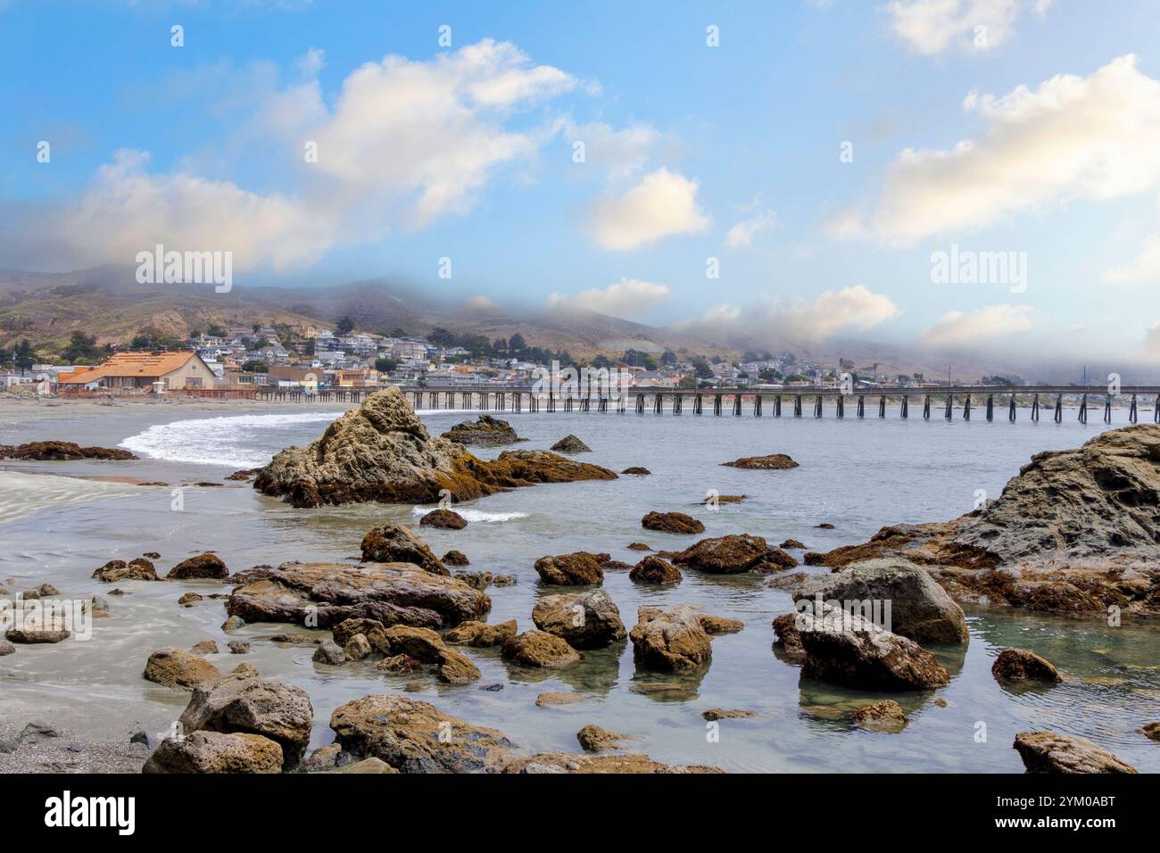 Cayucos Strand und Pier mit Felsen im Vordergrund, Kalifornien Stockfoto