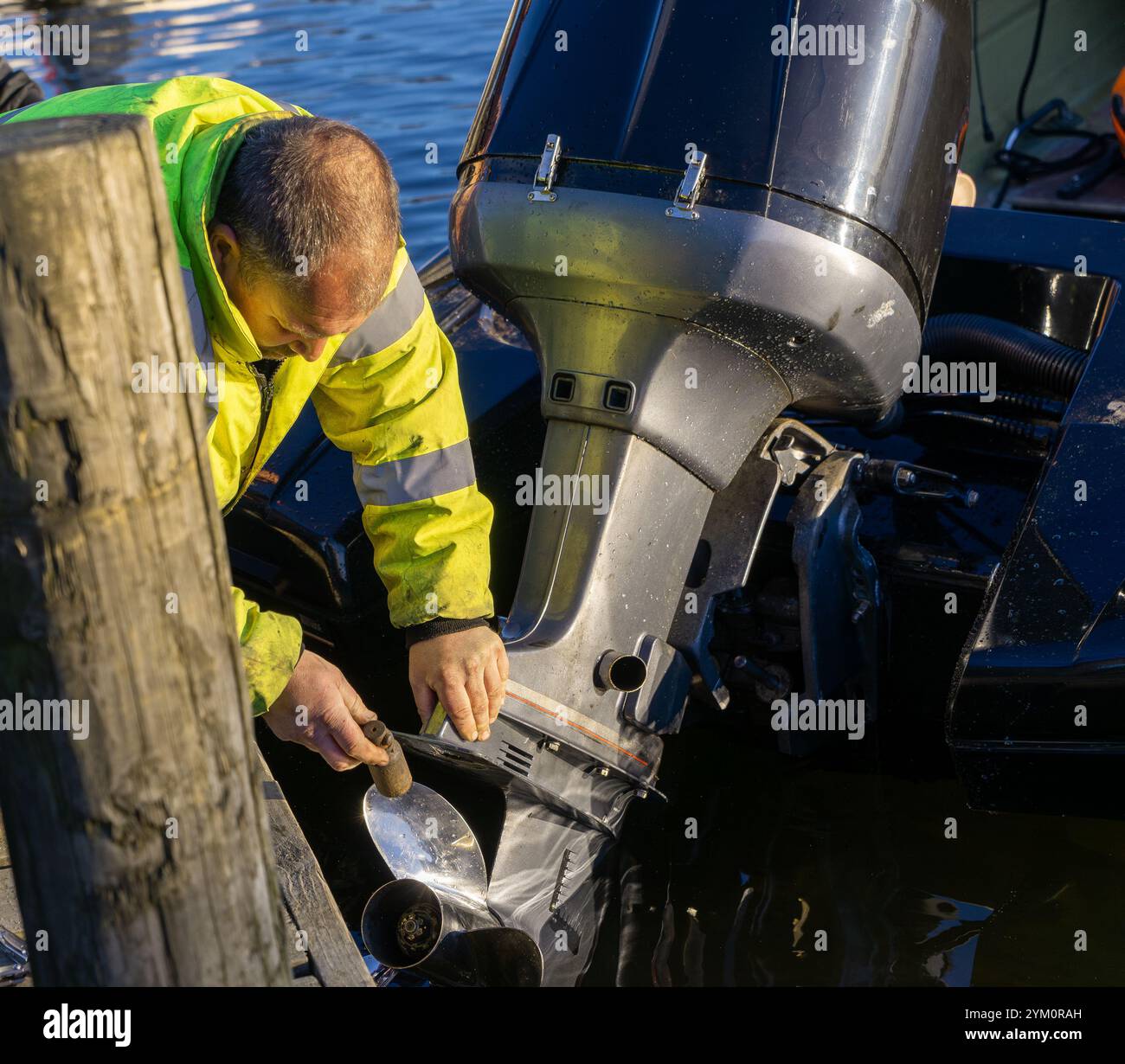 Ein Mann in einer Hi-Viz-Jacke arbeitet am Außenbordmotor eines Motorbootes bei der Coniston Power Boat Records Week 2021 auf Coniston Water im Lake District Stockfoto
