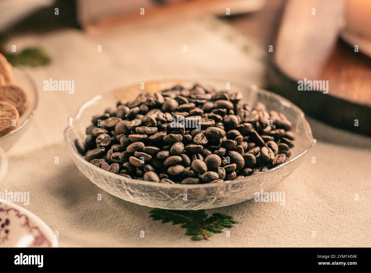 Kaffeebohnen oder Samen in einer Glas- oder Kristallschale auf einem Tisch, Vintage Hintergrund Stockfoto