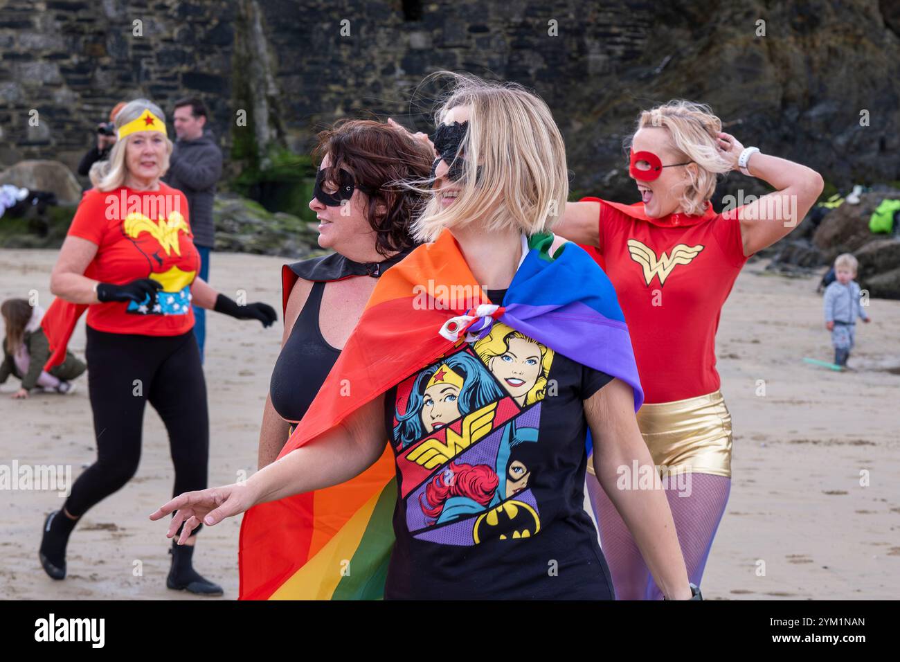 Die Teilnehmer treffen sich am Strand von Towan und bereiten sich auf die jährliche Veranstaltung „Superhero in the Cold“ vor, um Spenden für die britische Krebsforschung zu sammeln. Stockfoto