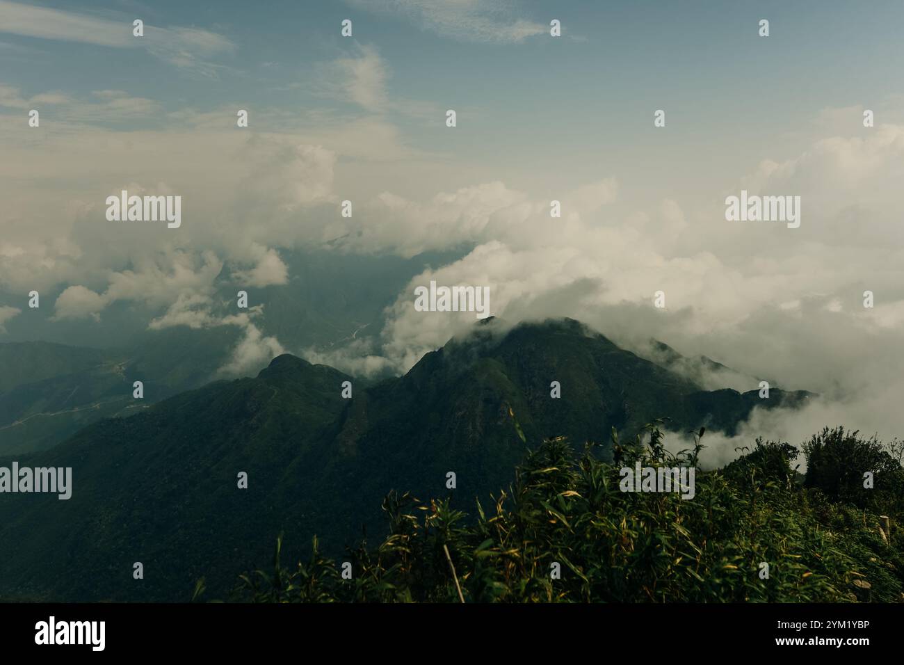 Atemberaubende Aussicht vom Gipfel des Fansipan Berges in Lai Chau, Vietnam, mit Wolken, die über die üppigen grünen Berge Rollen. Hochwertige Fotos Stockfoto