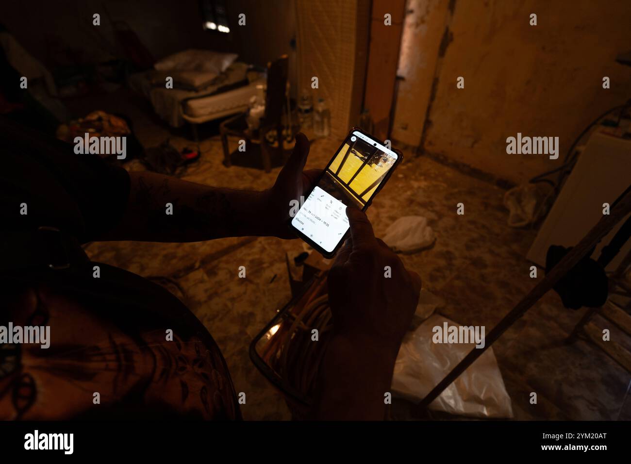 Alfafar, Spanien - 19. November 2024. Vicente, wohnhaft in Alfafar an der Torrente Avenue vor dem parque Alcosa, ließ sein Haus vollständig vom Wasserstrom untertauchen. Er zeigt die Höhe, die durch die Flut erreicht wurde, und zwei Fotos, die von derselben Stelle aufgenommen wurden, zum Fenster und zu den Straßenverhältnissen. In weniger als 15 Minuten stieg das Wasser um mehr als 1 Meter und das Motorrad (auf dem Foto) wurde weggefegt. Zu diesem Zeitpunkt hatten die Behörden noch nicht den roten Alarm gemeldet. Quelle: Roberto Arosio/Alamy Live News Stockfoto