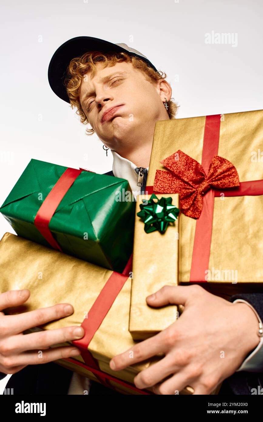 Ein Mann zeigt seine Weihnachtsmode, während er stolz bunte Geschenkverpackungen hält. Stockfoto