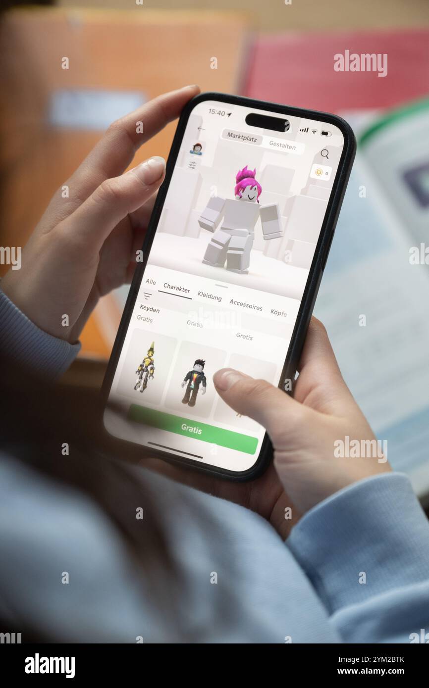 ILLUSTRATION - 20. November 2024, Baden-Württemberg, Stuttgart: Ein Mädchen betreibt ein Smartphone, auf dem die Roblox-App zu sehen ist (posierte Szene). Foto: Marijan Murat/dpa Stockfoto