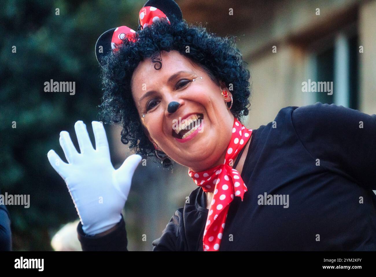 Eine Person in einem Kostüm, das Minnie Mouse ähnelt, einer bekannten Zeichentrickfigur. Ein schwarzes Oberteil, ein rotes Stirnband mit Polka Dots und Maus Stockfoto