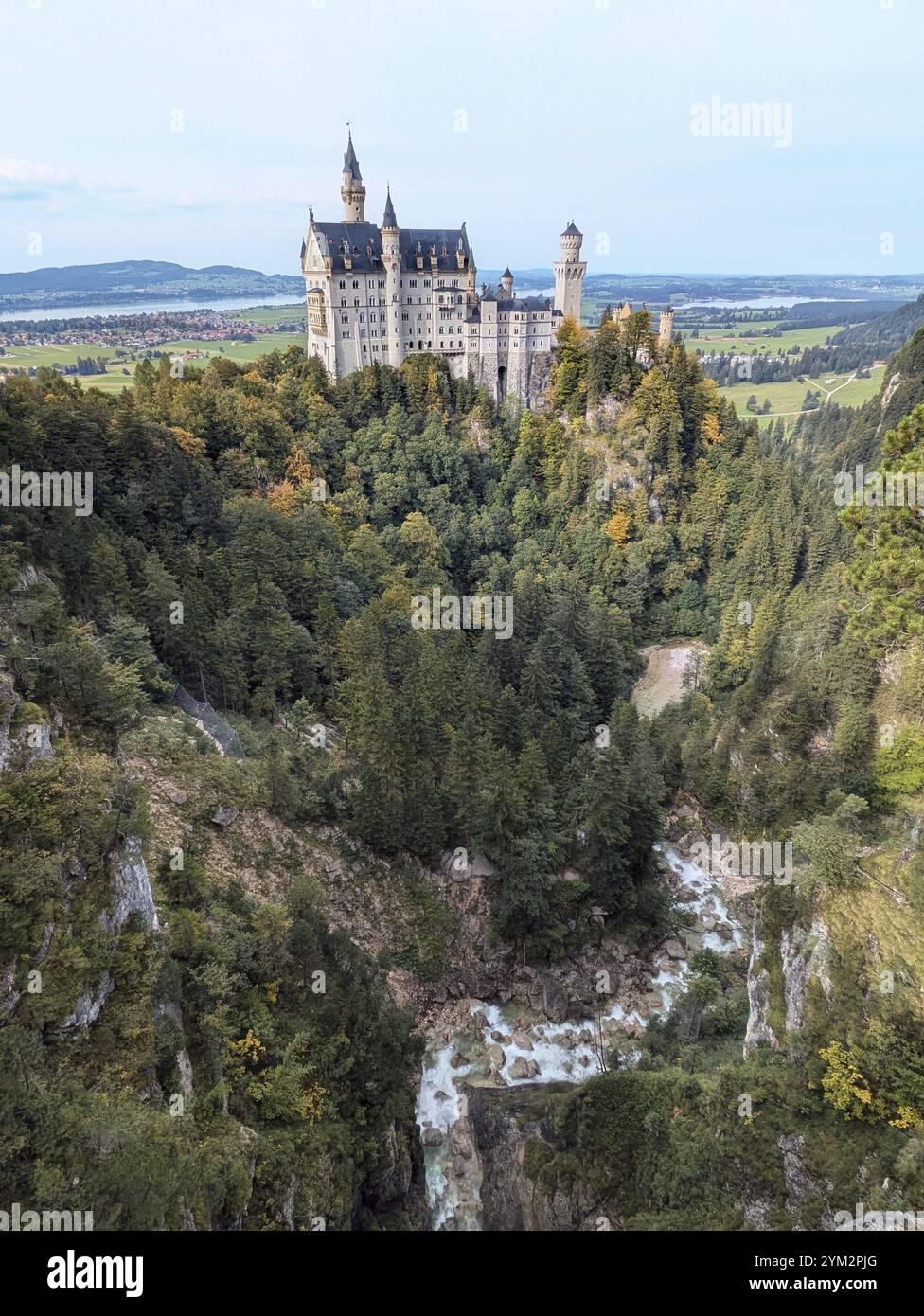 Schloss Neuschwanstein, ein märchenhaftes Schloss inmitten eines üppig grünen Waldtals, umgeben von einem üppig grünen Wald und einem fließenden Fluss in einer Ma Stockfoto