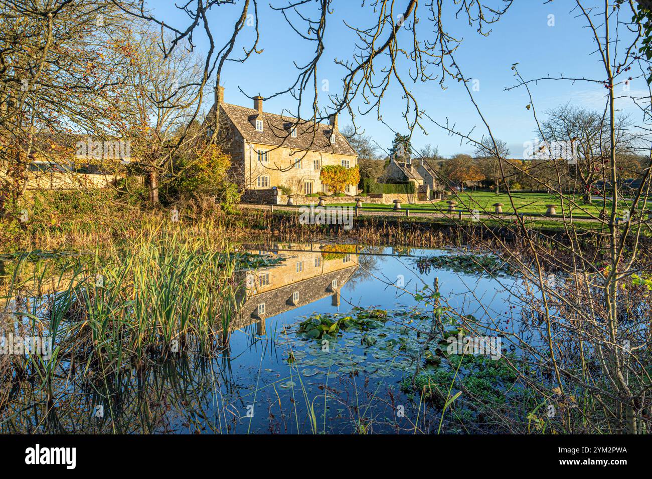 Abendlicht auf der College Farm neben dem Teich auf dem Grün im Dorf Cotswold in Wyck Rissington, Gloucestershire, England Großbritannien Stockfoto