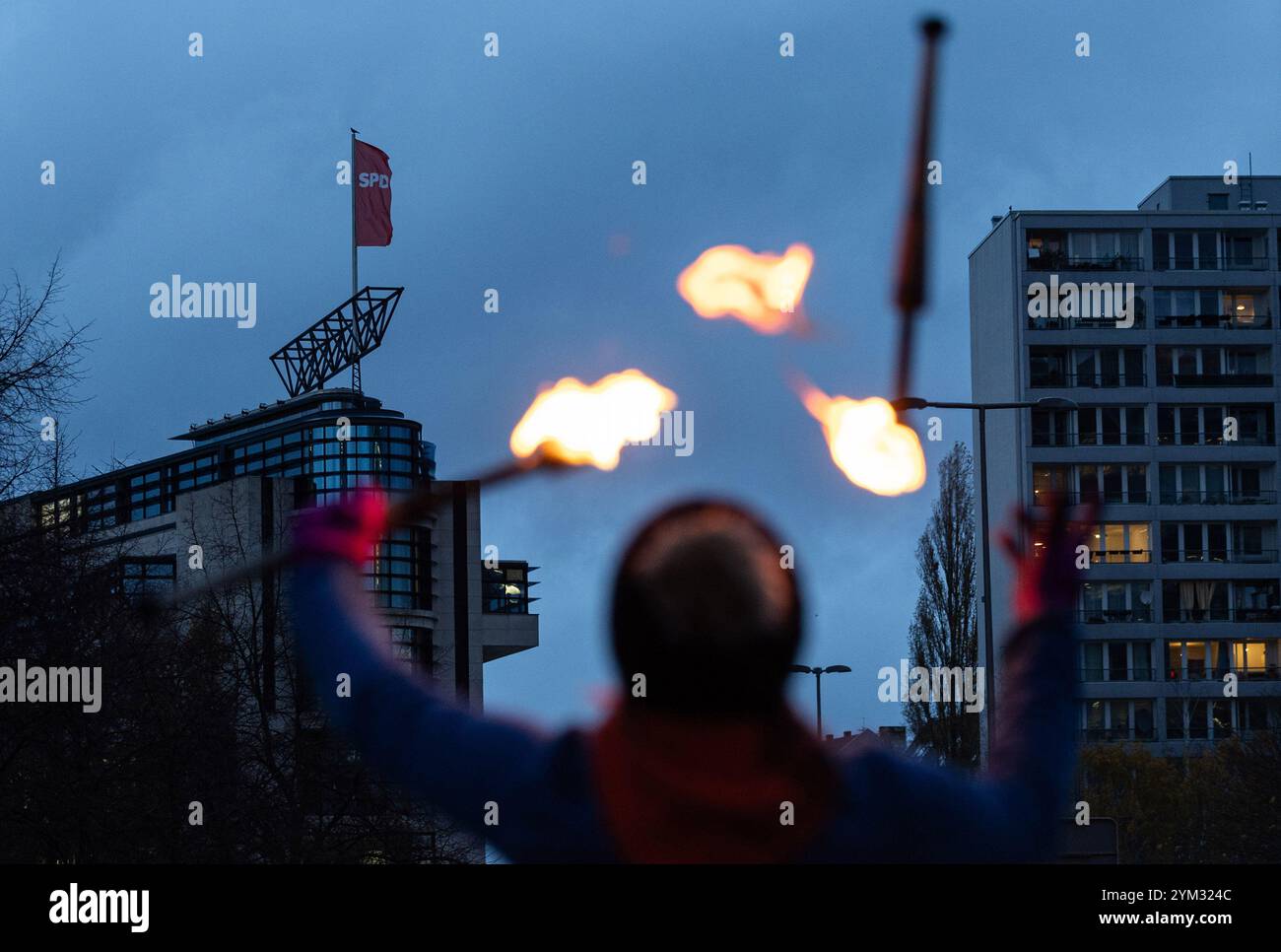 Berlin, Deutschland. November 2024. RECROP Ein Straßenkünstler jongliert mit Fackeln vor dem SPD-Partyquartier im Willy-Brandt-Haus. Die SPD prüft derzeit ihren Kanzlerkandidaten bei den anstehenden Bundestagswahlen. Quelle: Hannes P. Albert/dpa/Alamy Live News Stockfoto