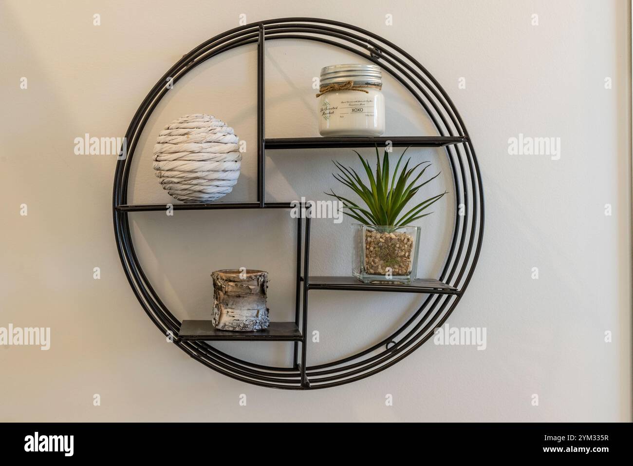 Ein schwarzes Metallregal mit einer weißen und grünen Pflanze darauf. Das Regal hat eine weiße Vase und eine weiße Kugel darauf Stockfoto