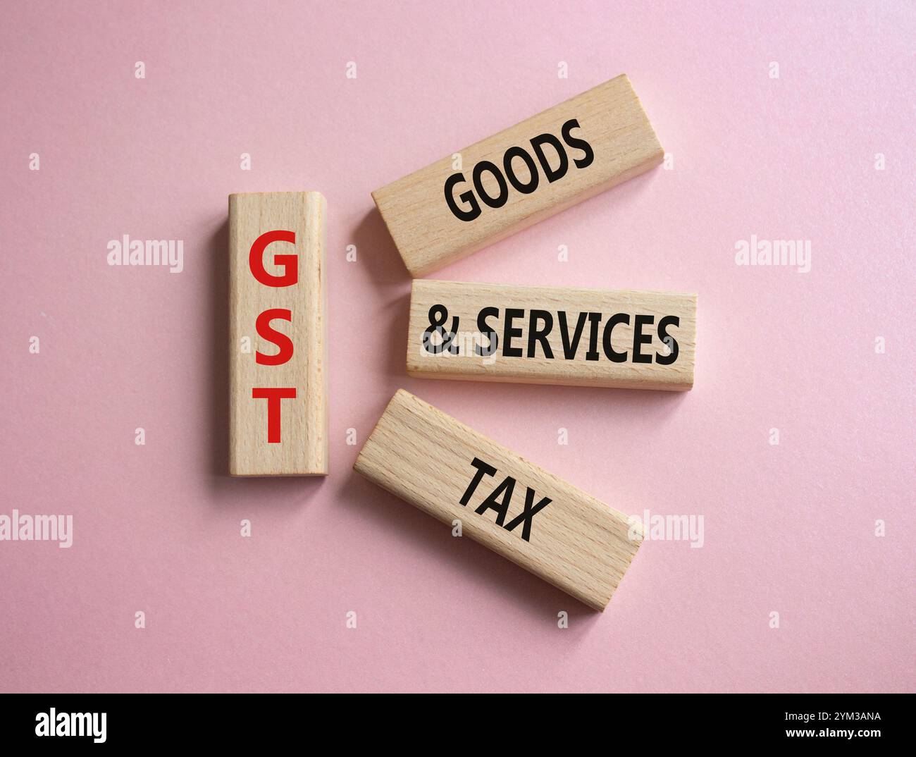 GST – Steuersymbol für Waren und Dienstleistungen. Konzeptwort GST auf Holzblöcken. Schöner rosafarbener Hintergrund. Business- und GST-Konzept. Kopierbereich. Stockfoto
