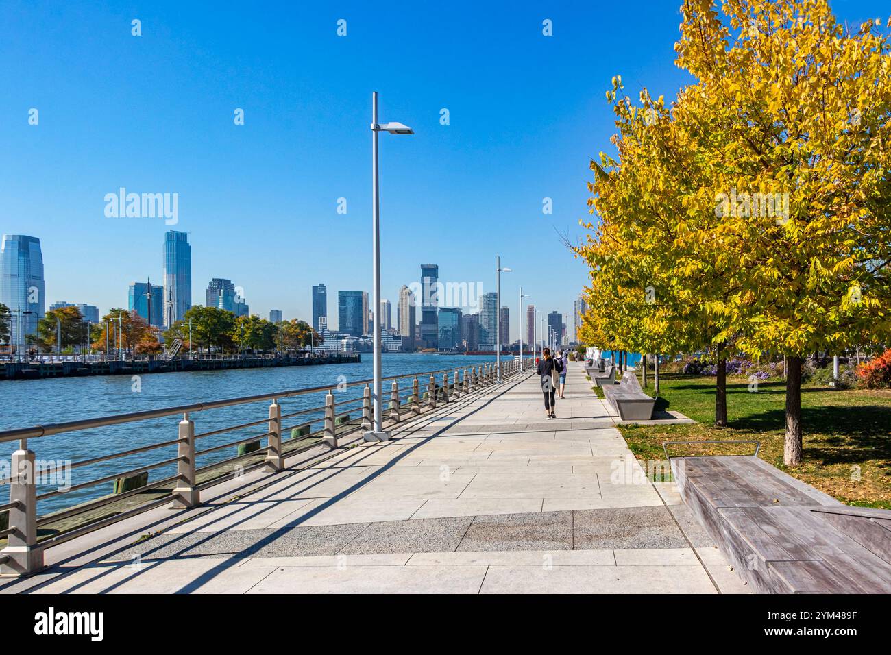 Sonniger Tag an einem Pier 26 am Fluss mit Joggingern, Herbstbäumen, New Jersey City Skyline im Hintergrund manhattan New york Stockfoto