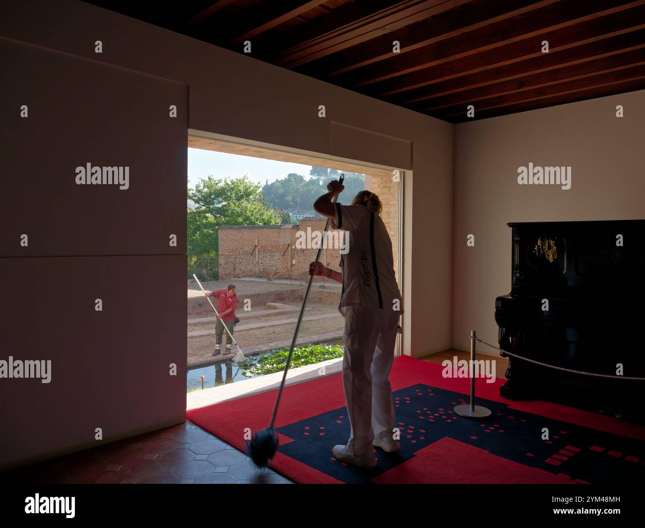 Ein Arbeiter reinigt in der Alhambra, während ein anderer draußen arbeitet Stockfoto