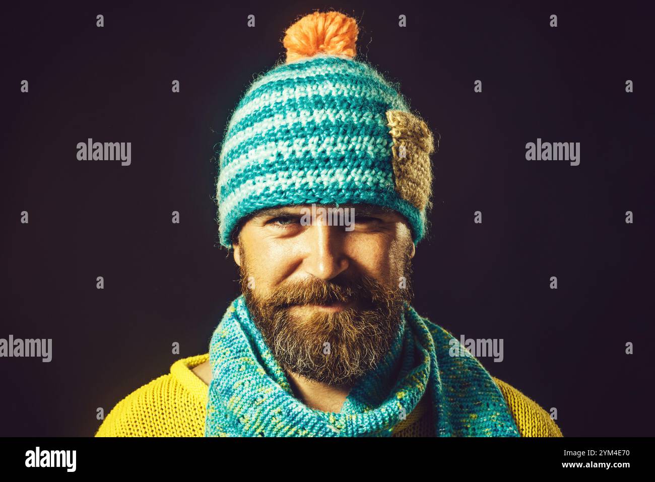 Nahaufnahme Porträt eines lächelnden bärtigen Mannes in Strickpullover, Schal und Hut. Modischer Mann in Winterkleidung. Lässige Wintermode für Herren. Gut Aussehend Stockfoto