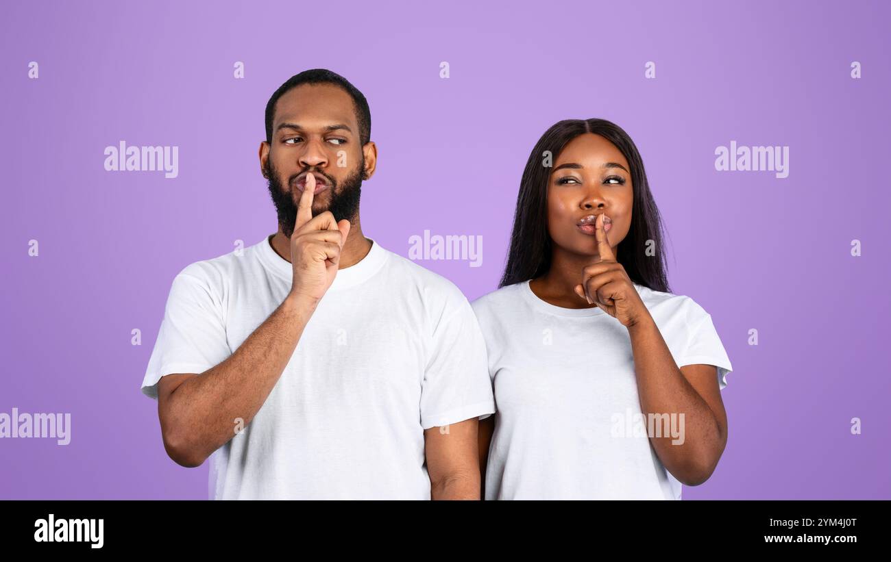 Schwarzes Paar, das Finger auf die Lippen stampft und ein Zeichen für die Stille macht Stockfoto