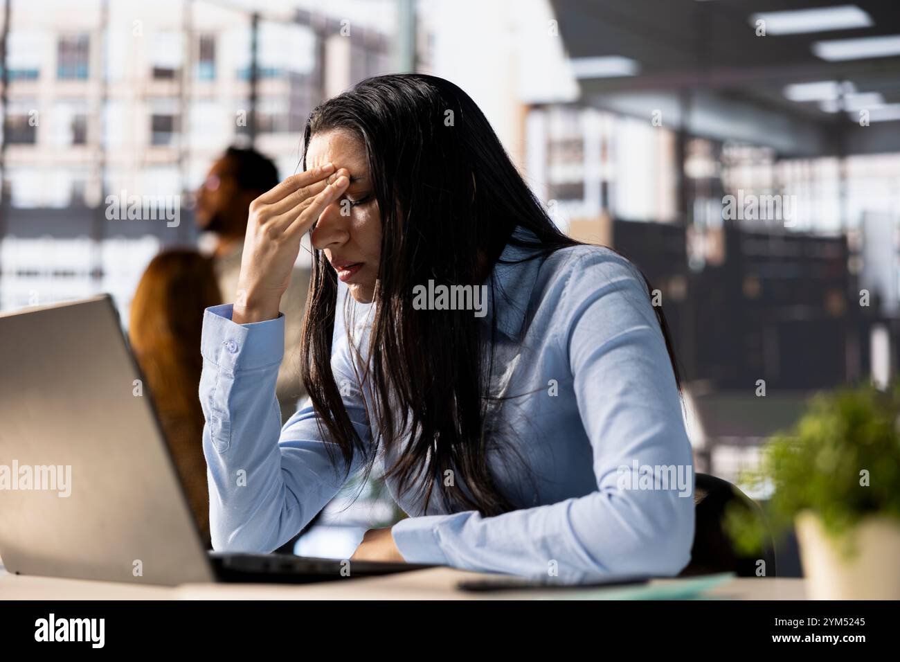 Eine gestresste Geschäftsfrau an ihrem Laptop fühlt den Druck von Projektterminen und emotionalen Belastungen. Die besorgte General Managerin geht mit Müdigkeit und Burnout um, was ihren Arbeitstag zu einer Herausforderung macht. Stockfoto