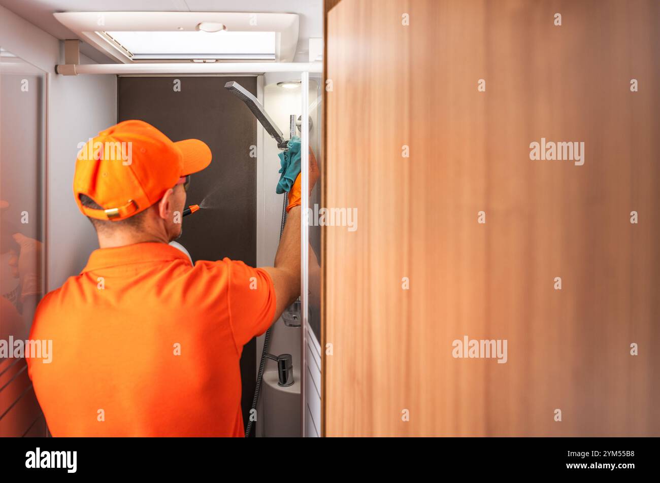 Ein Wartungspersonal in orangefarbener Uniform reinigt die Toiletten für Wohnmobile Stockfoto