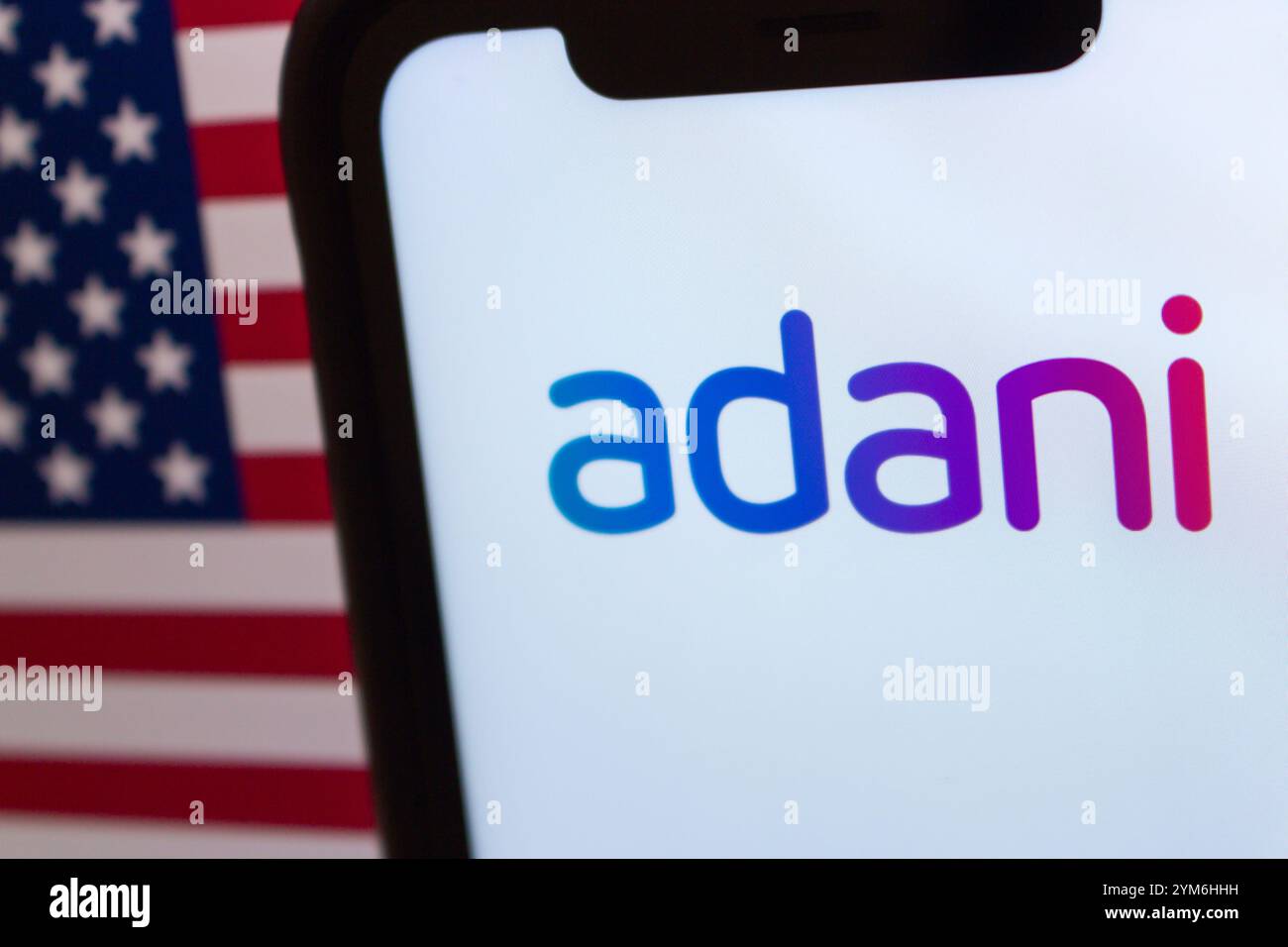 Das Firmenlogo von Adani mit US-Flagge im Hintergrund symbolisiert die wachsende Präsenz der Adani Group unter der rechtlichen und politischen Kontrolle der USA Stockfoto