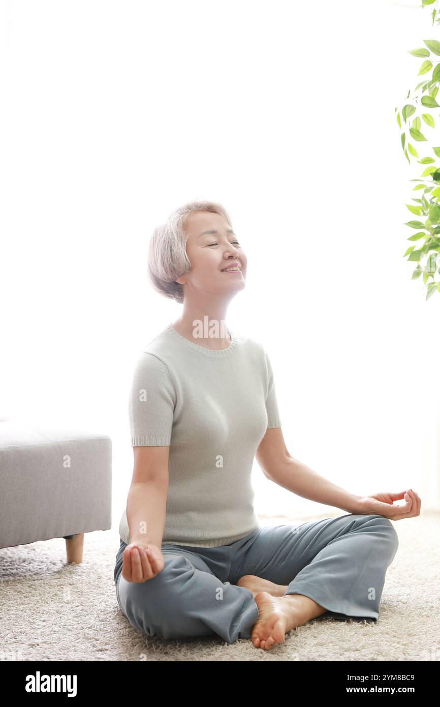 Ältere Frau in Yoga-Grundhaltung mit geschlossenen Augen Stockfoto