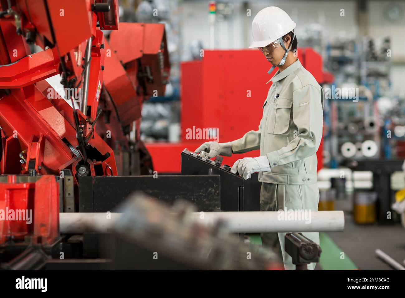 Mann in Arbeitskleidung, der eine Maschine bedient Stockfoto