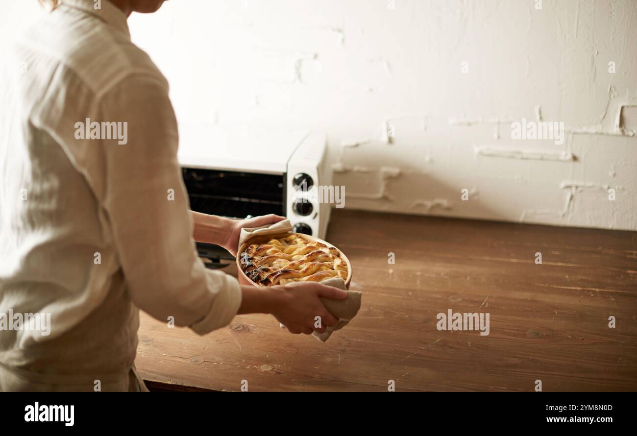 Eine Frau, die einen gebackenen Kuchen aus dem Ofen nimmt Stockfoto