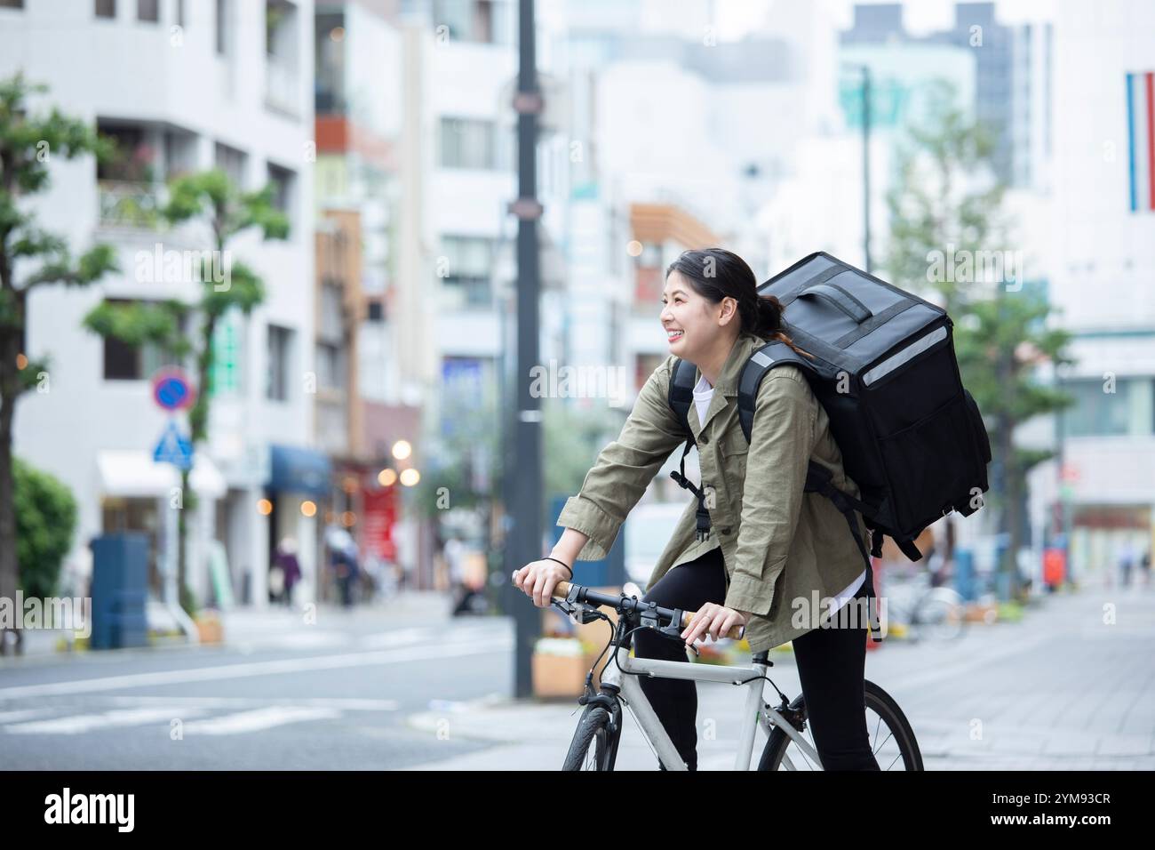 Eine junge Frau, die Pakete mit dem Fahrrad liefert Stockfoto