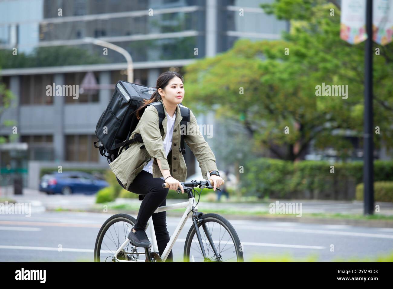 Eine junge Frau, die Pakete mit dem Fahrrad liefert Stockfoto