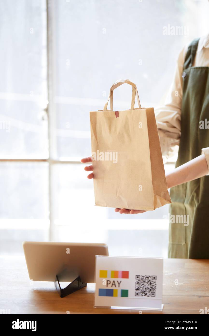 Weibliche Ladeninhaberin an der Kasse mit bargeldloser Zahlung Stockfoto