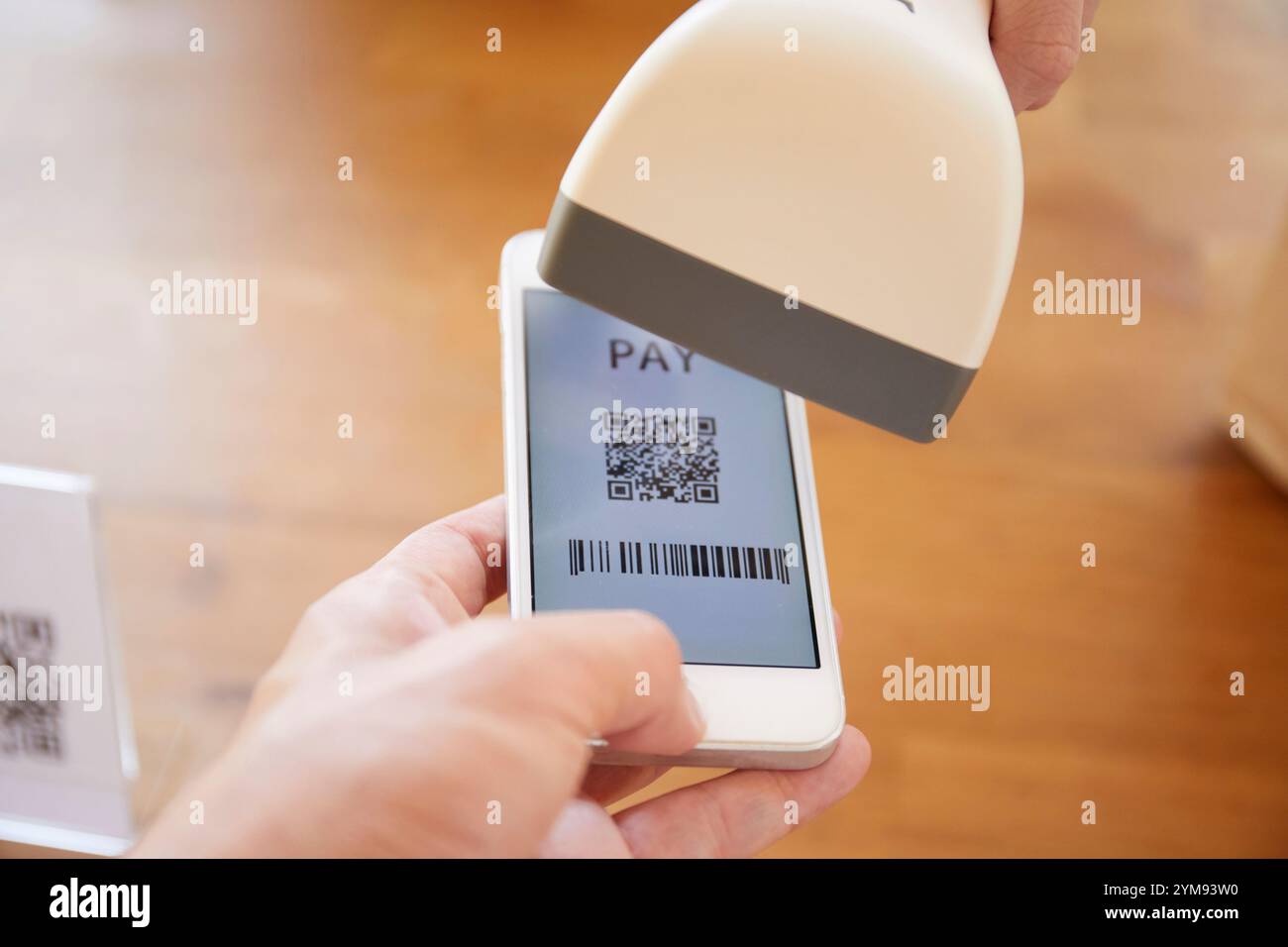 Hände an der Kasse mit einem Smartphone, um eine Zahlung zu tätigen Stockfoto