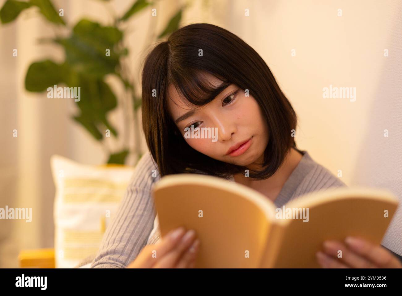 Eine junge Frau, die nachts in ihrem Zimmer relaxt Stockfoto