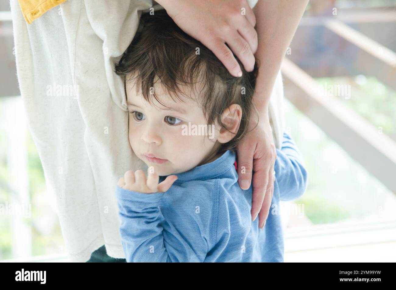 Jungs, die sich an die Beine ihrer Mutter Klammern Stockfoto