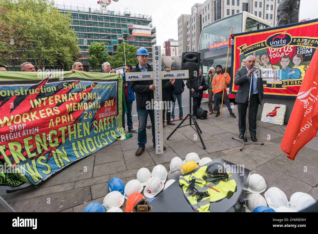 London, Großbritannien. April 2017. Jerry Swain, der nationale Baubeamte von Unite 500, stellt die International Workers&#8217; Memorial Day Rallye vor, die an die Statue eines Bauarbeiters auf Tower Hill erinnert, an all jene, die in den letzten zehn Jahren bei der Arbeit ums Leben kamen, vor allem in der Bauindustrie, sowie an die Verletzten, Behinderten und Unwohlhabenden, fast alle durch vermeidbare Zwischenfälle. In seiner Mitte stand ein Sarg mit Stiefeln, Schutzhelm, hochauflösendem tabard und Schutzbrille, umgeben von weiteren Helmen, einer für jeden der 43 Arbeiter, die dieses Jahr getötet wurden. Der Slogan für den Tag war "Remember the Dead - Figh Stockfoto