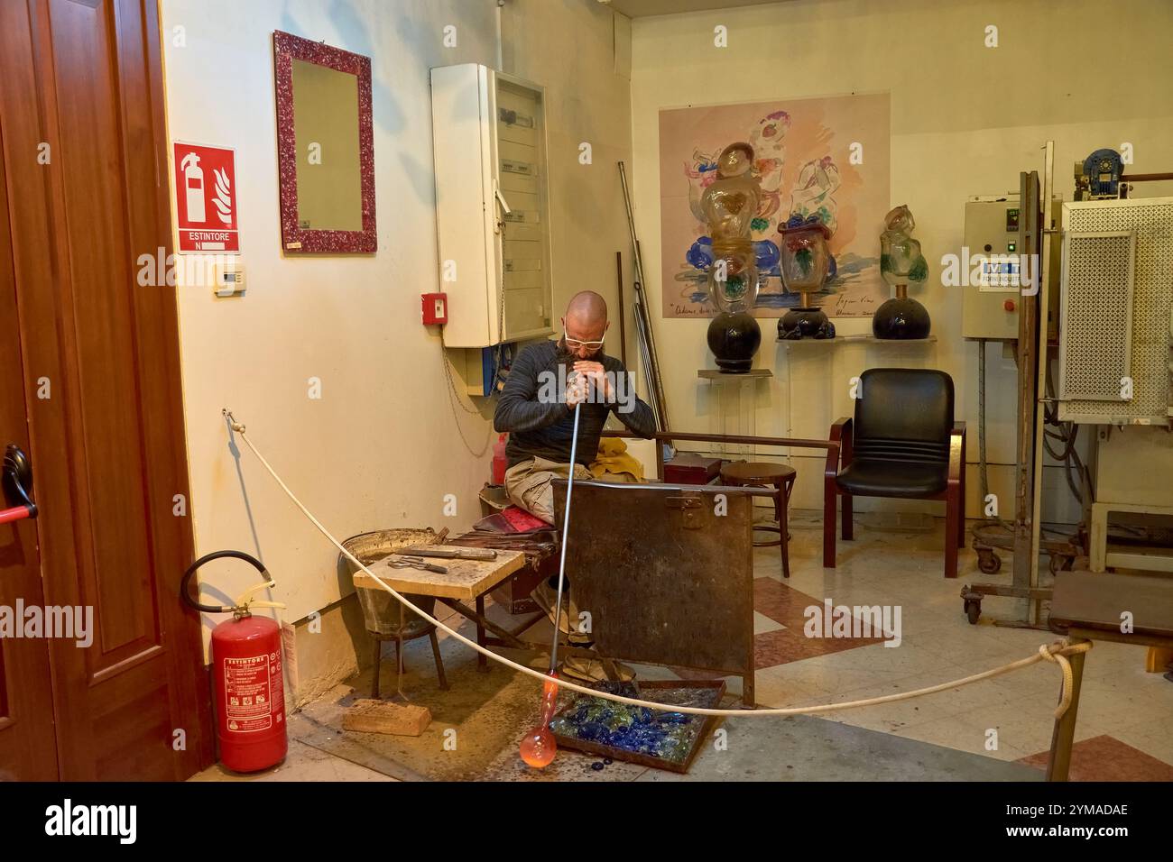 Venedig, Italien; 17. Oktober 2024: Ein schwieriger Prozess der Herstellung einer Murano-Glasfigur in einer historischen venezianischen Werkstatt. Der geschickte Handwerker formt sorgfältig Stockfoto