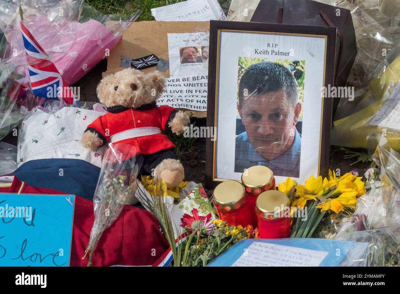 April. Zehn Tage nach dem Terroranschlag in Westminster halten die Menschen immer noch an, um die Blumen für die Opfer zu suchen und zu fotografieren, darunter PC Keith Palmer, auf einem gerahmten Foto, entlang der gesamten Front des Parliament Square. Stockfoto