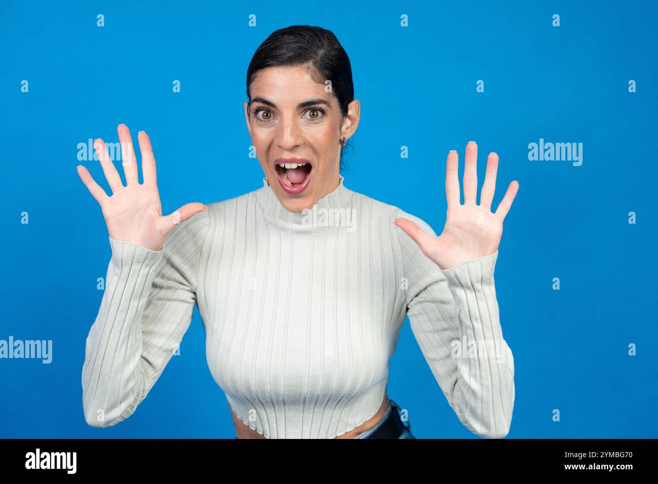 Die brünette Frau zeigt zehn Finger mit beiden Händen und schreiend auf blauem Hintergrund Stockfoto