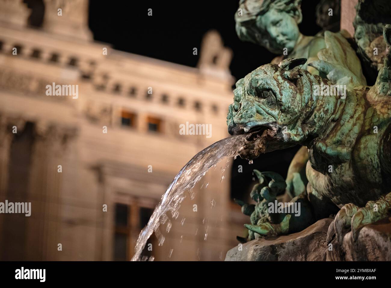 Alter, verwitterter, bronzener Wasserbrunnen-Statuenkopf mit Wasser, das aus dem Mund strömt. Nahaufnahme, Nachtaufnahme, geringe Schärfentiefe, keine Leute Stockfoto