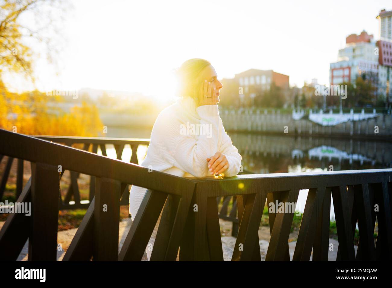 Frau in weißem Pullover, die sich auf die Brücke lehnt Stockfoto