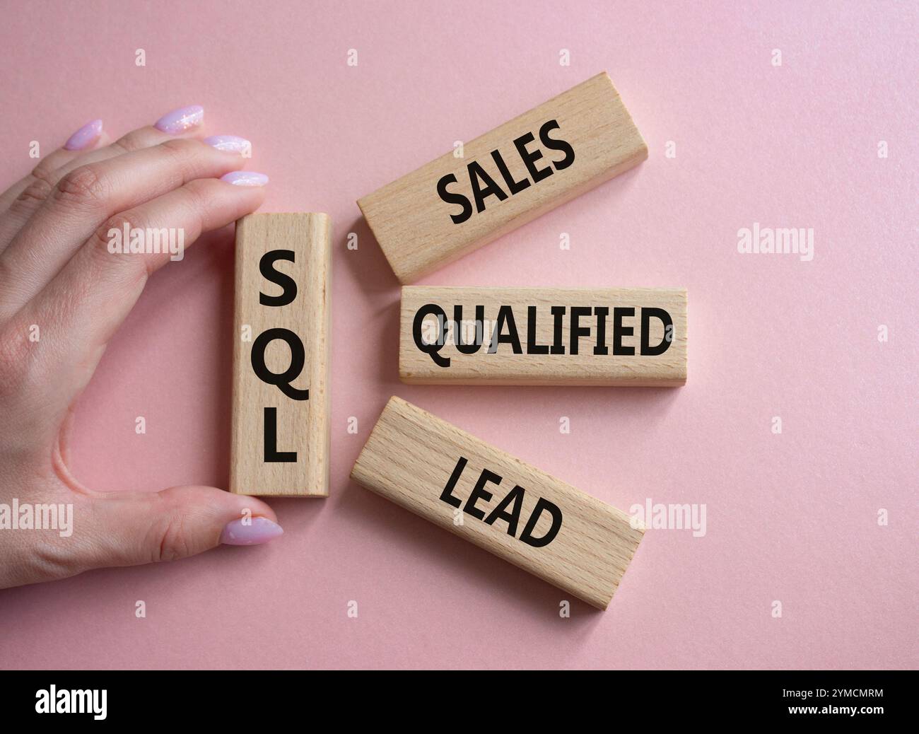 SQL - qualifizierter Lead für Vertrieb. Holzwürfel mit SQL-Wörtern. Geschäftsmann Hand. Schöner rosafarbener Hintergrund. Business- und SQL-Konzept. Kopierbereich. Stockfoto