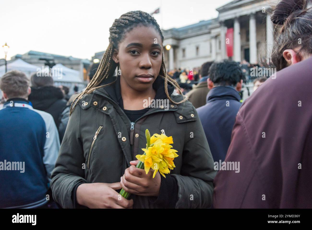 März 2013. Frau mit Narzissen. Tausende von Londonern kamen zum Trafalgar Square, um an einer Mahnwache teilzunehmen, die vom Londoner Bürgermeister Sadiq Khan einberufen wurde, um ihren Respekt für die Toten und Verletzten beim gestrigen Terroranschlag zu zeigen und darauf zu bestehen, dass die Londoner sich nicht einschüchtern lassen und gemeinsam gegen Hass und Spaltung stehen. Nach Reden von Polizei, Innenminister und Bürgermeister gab es eine Schweigeminute und drei große Kerzen wurden angezündet. Viele in der Menge hielten auch Kerzen oder Blumen und legten sie auf den Platz. Stockfoto