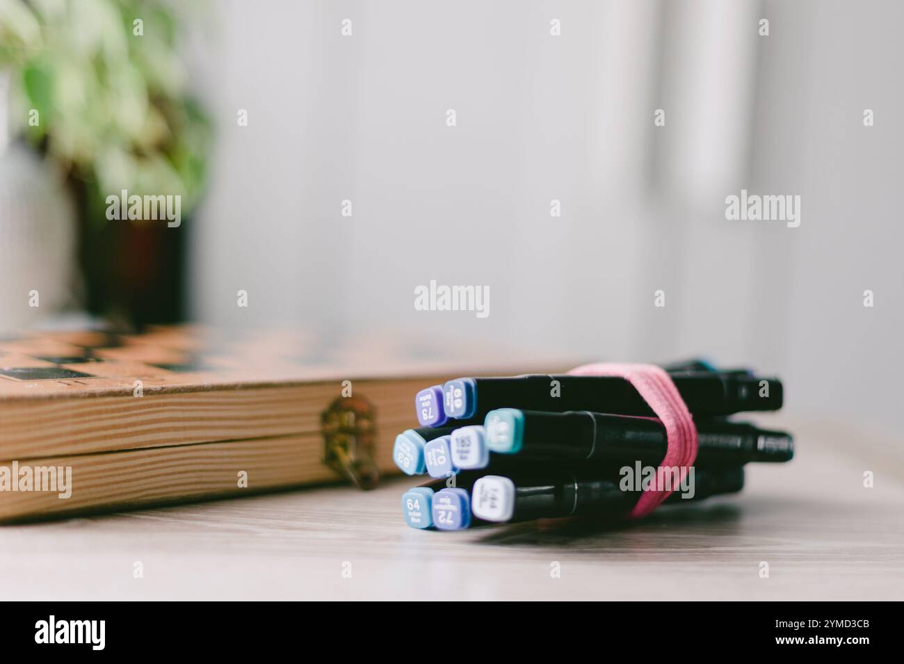 Ein Haufen Stifte stehen auf einem Tisch neben einem Buch. Die Stifte sind schwarz und blau Stockfoto