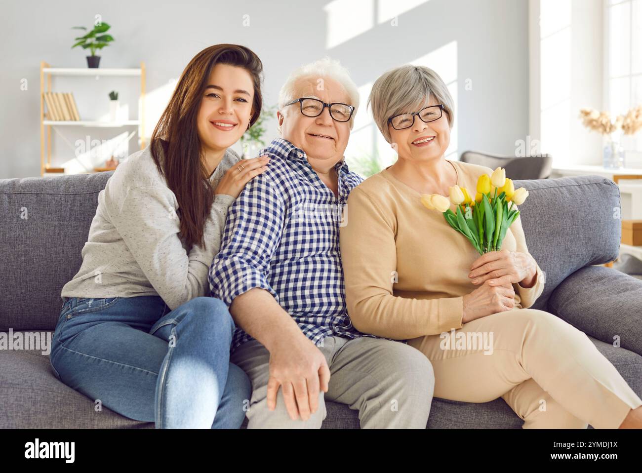 Glückliche Familie alte Eltern Erwachsene Tochter sitzt auf Sofa im Wohnzimmer und lächelt zusammen. Familiäre Atmosphäre alte Eltern lieben ihre Tochter Stockfoto