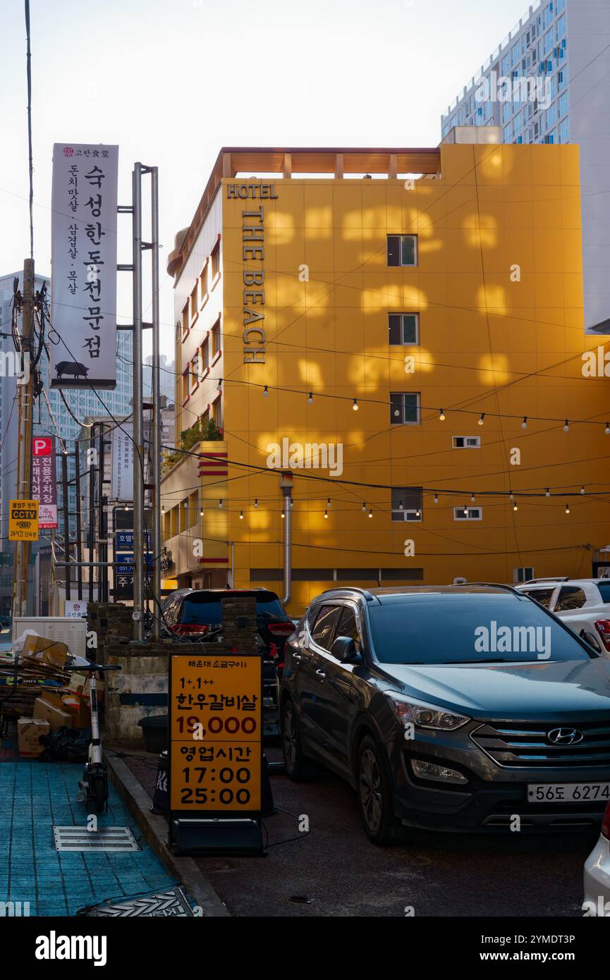 Urbane Straßenszene mit gelber Hotelfassade, Autos und Beschilderung in Busan, Südkorea. Stockfoto
