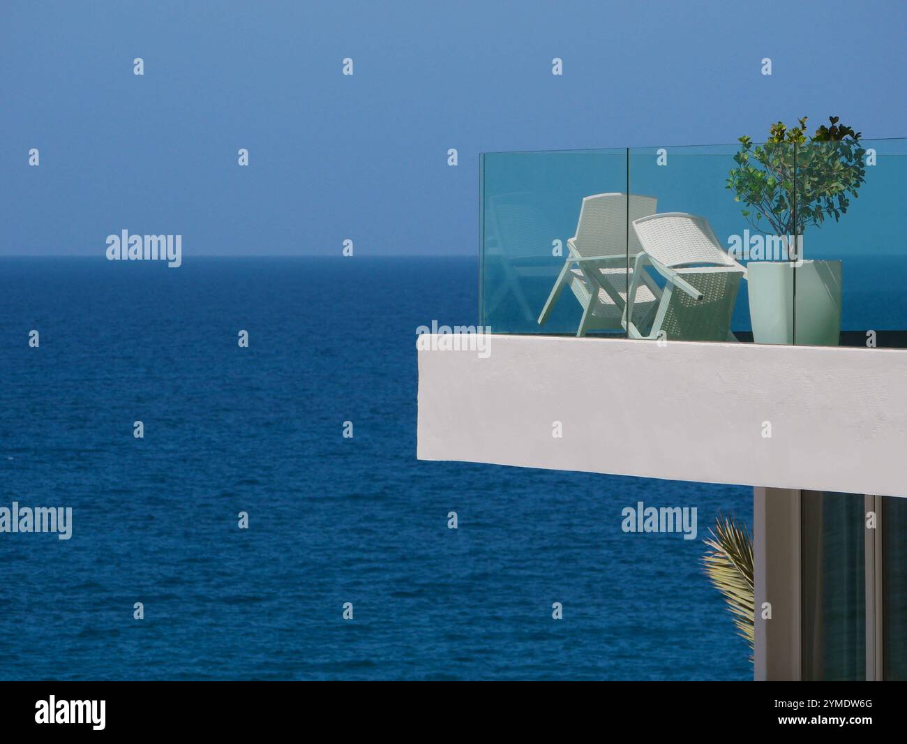 Luxuriöser Balkon mit Panoramablick auf das Meer. Innenterrasse des Resorts mit Meerblick, Tisch, Stühlen und Topfpflanzen. Stockfoto