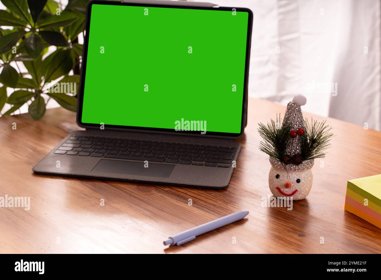 Der moderne Tablet-Computer-Arbeitsplatz mit weihnachtsschmuck bringt Weihnachtsstimmung auf den Holztisch mit Pflanzen Stockfoto