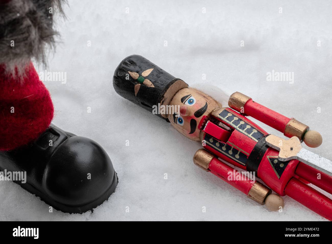 Liegend verlassenes Nussknacker-Spielzeug und Santa Claus Füße auf einem schneebedeckten Boden Stockfoto