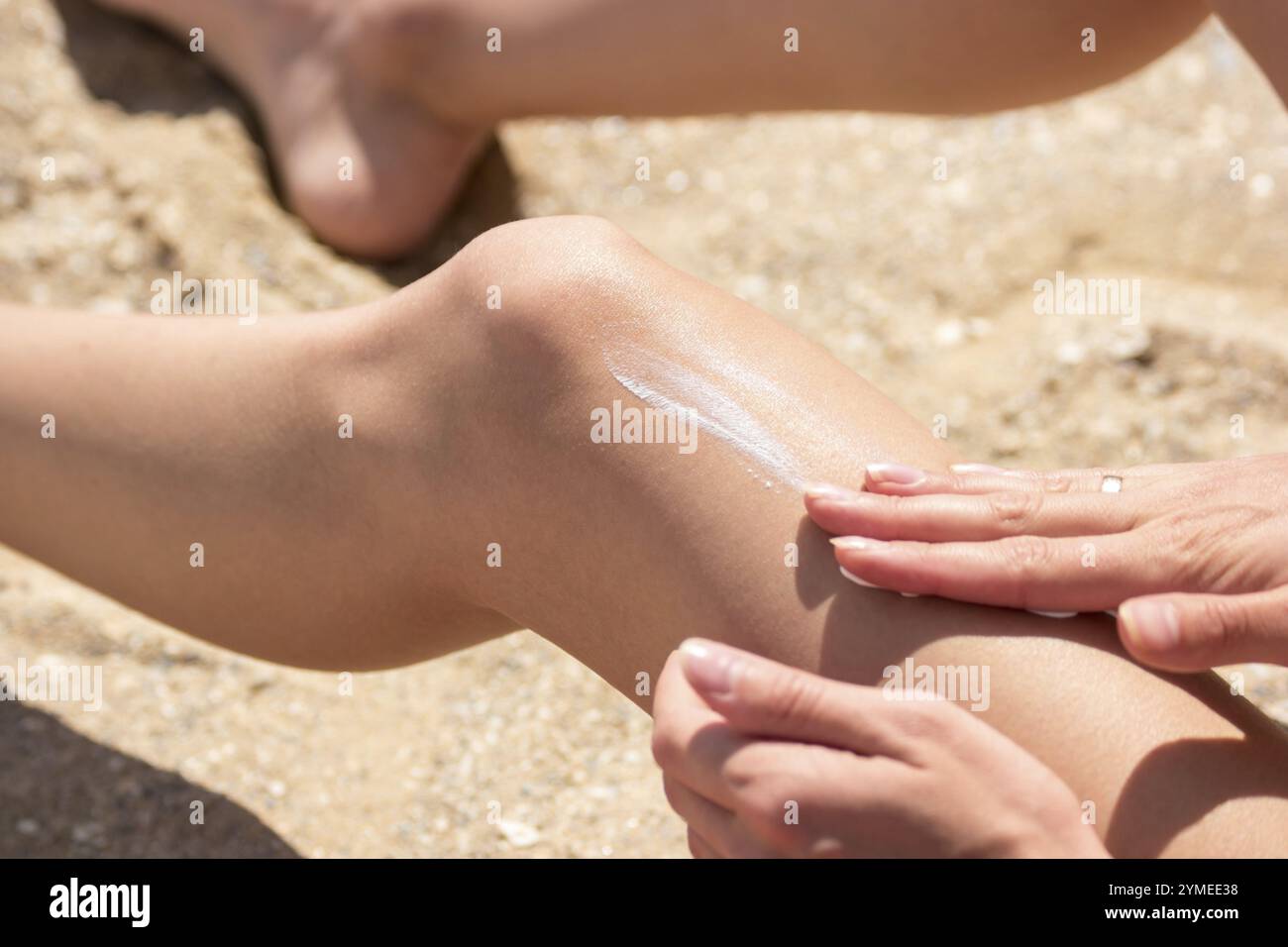 Die Dame trägt Sonnencreme auf das Bein. Hände der jungen Frau. Lassen Sie sich im Urlaub bräunen. Schutz für Ihre Haut Stockfoto