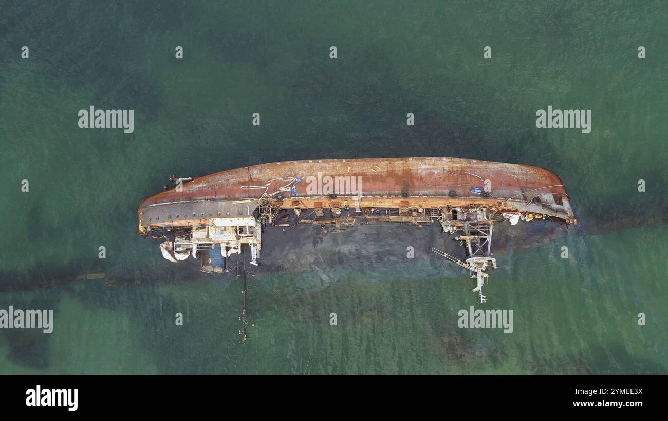 Ein kaputtes, rostiges Öltankschiff im Flachwasser umgekippt. Ertrunkenes Schiff nach dem Wrack Stockfoto