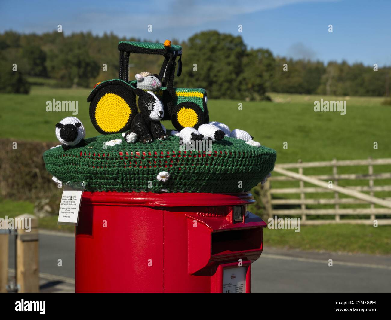 Nahaufnahme der Garn Bomb auf rotem Briefkasten (Ausstellung der Farm-Szene, dekorative Garn-Bombenbombe Street Art) - Bolton Abbey Village, North Yorkshire, England Großbritannien. Stockfoto