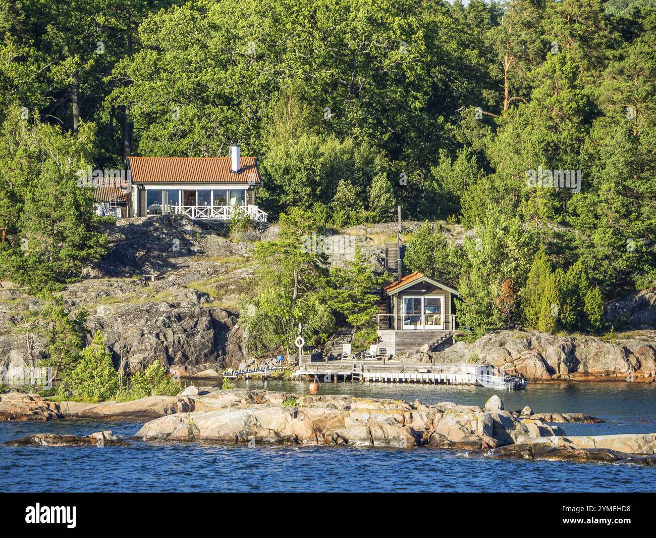 Zwei Cottages eingebettet in eine bewaldete Felsenlandschaft am See, Archipel, stockholm, schweden Stockfoto
